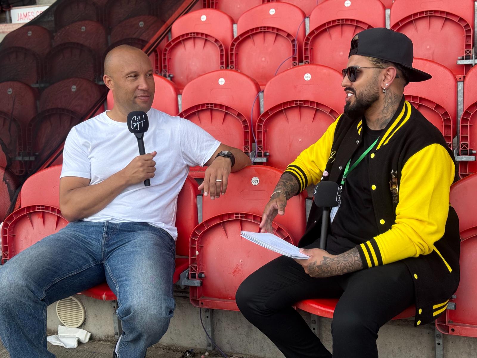 Gerryn Hussain interviewing a guest pitchside with his GH microphone